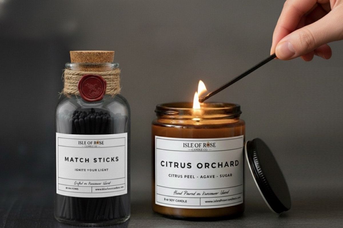 Candle labeled 'Citrus Orchard' being lit next to a bottle of 'Match Sticks' on a dark background