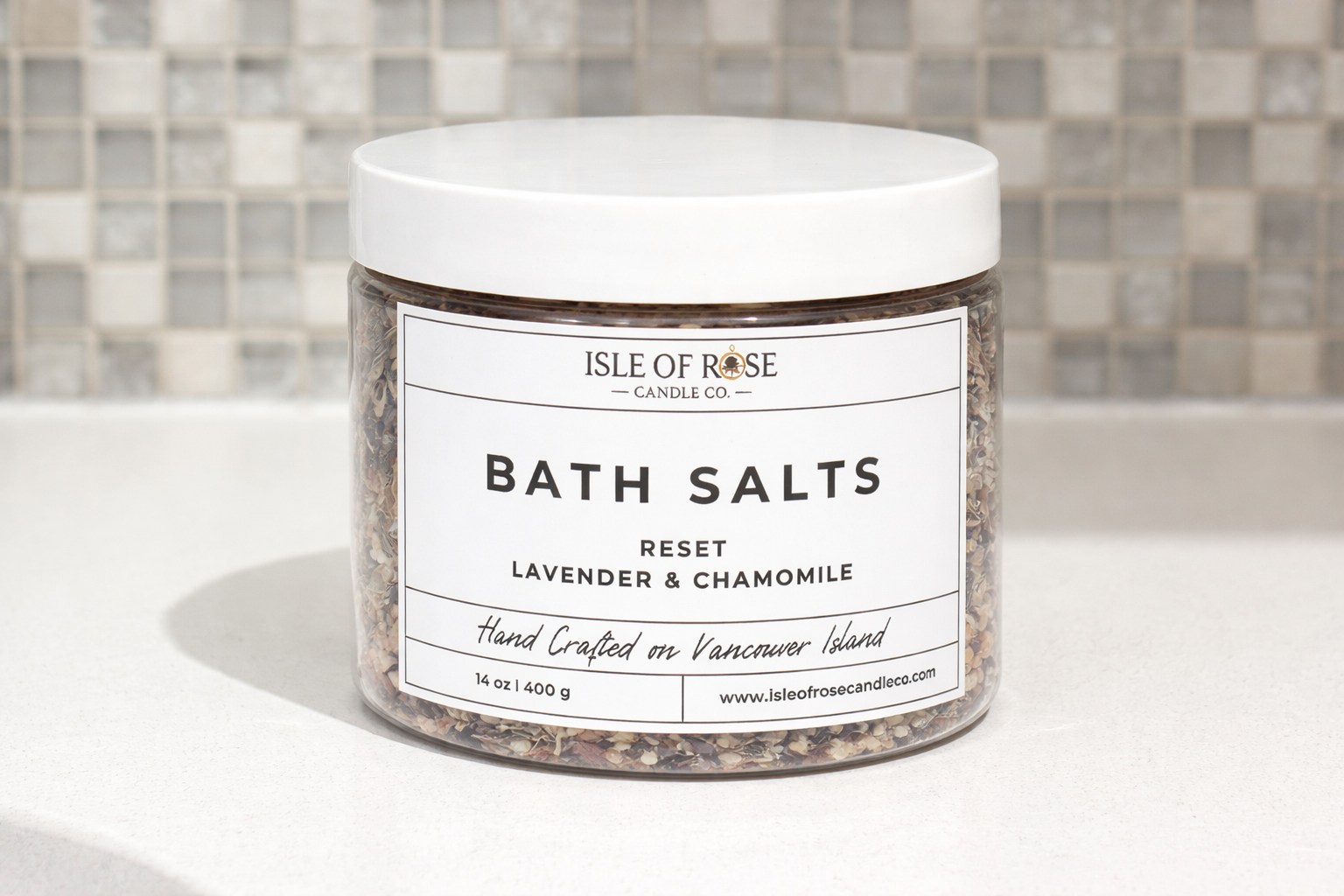 Jar of Isle of Rose Candle Co bath salts on a bathroom counter with a tiled wall background.