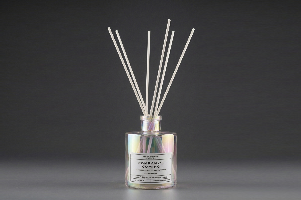 Reed diffuser with labeled bottle on a dark background