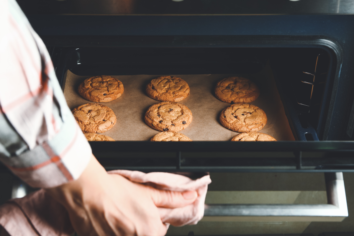 Person taking a tray of cookies out of an oven