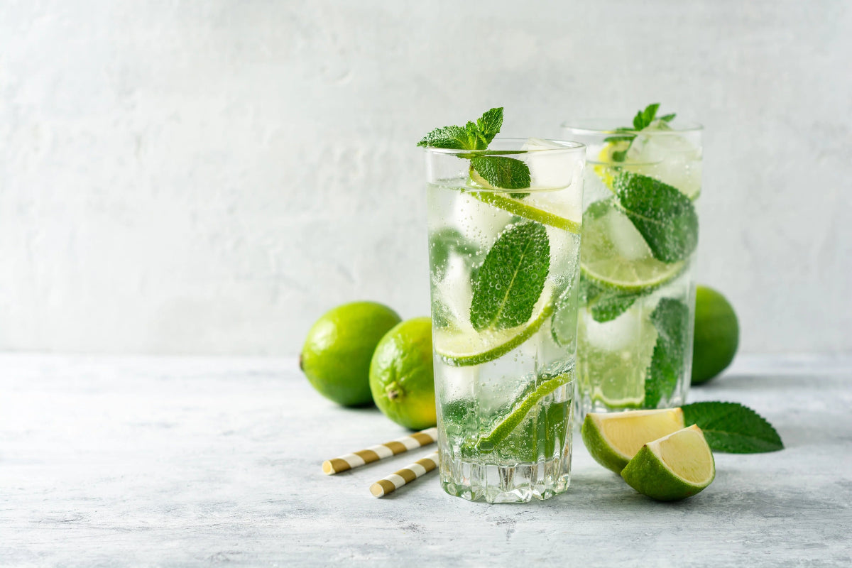 Two glasses of lime and mint infused water on a light wooden surface. Rum