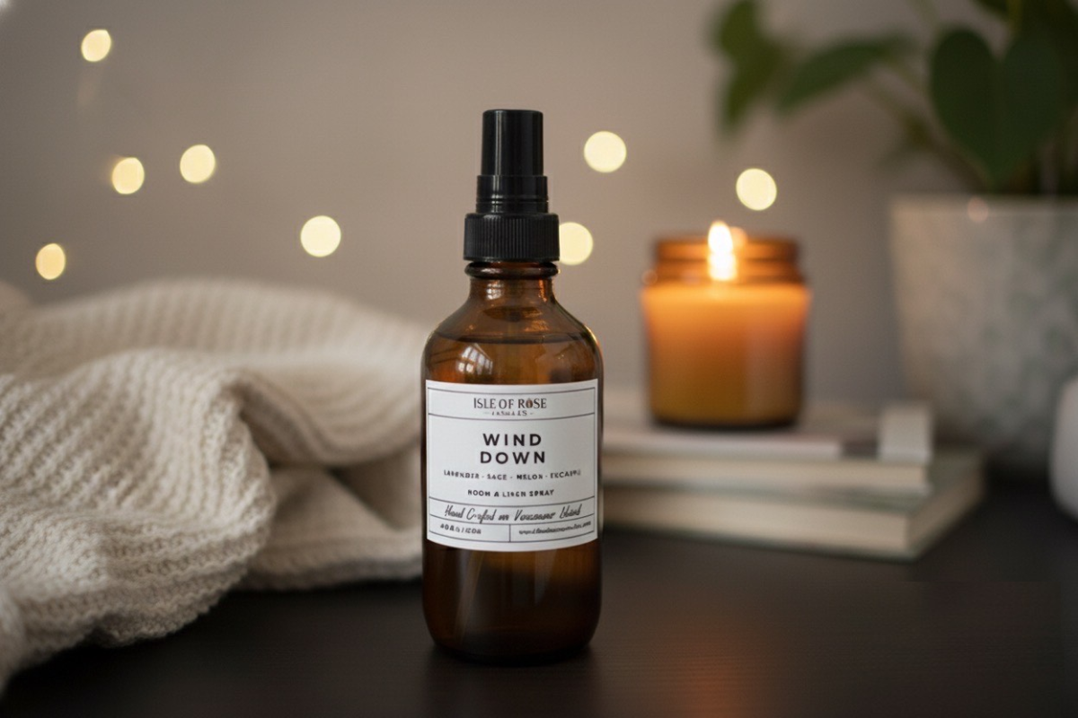 Bottle of 'Wind Down' spray with a candle and cozy blanket in the background